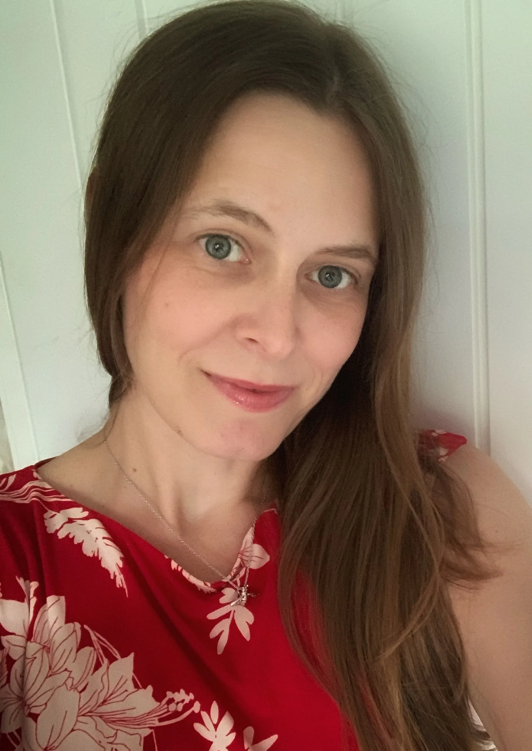 Dr Kathryn Jones, smiling, in a red floral top against a white panelled wall.